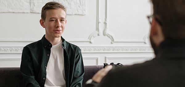 A young man talking with a therapist during a psychotherapy session